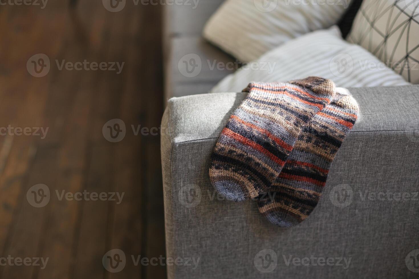Pair of hand knitted socks on the sofa in modern interior. photo