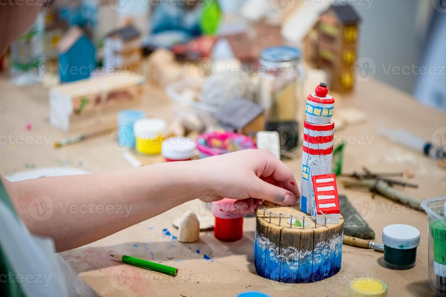 cute teen girl at a master class making a DIY wooden lighthouse made of wood, exhibition of crafts, crafts fair, education, master classes photo