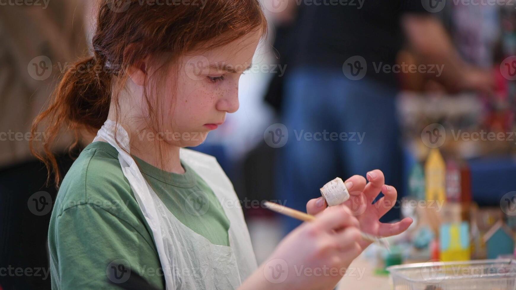 girl makes a wooden product with her own hands, paints it with white paint photo