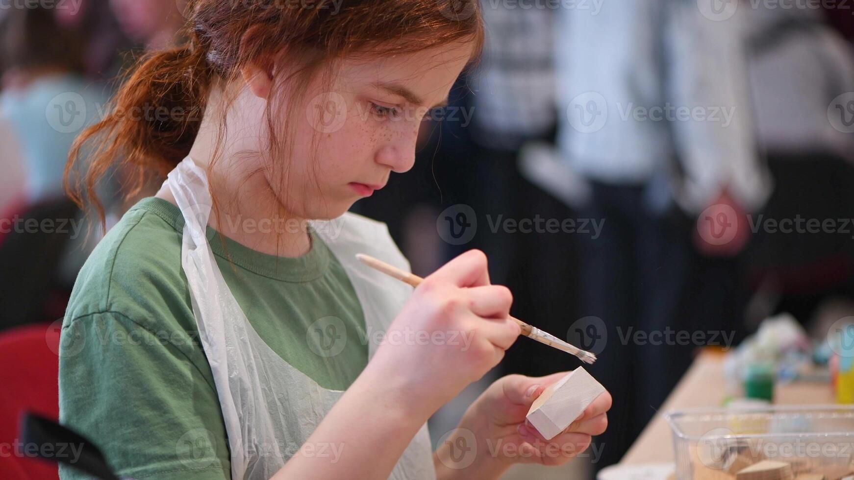 girl makes a wooden product with her own hands, paints it with white paint photo
