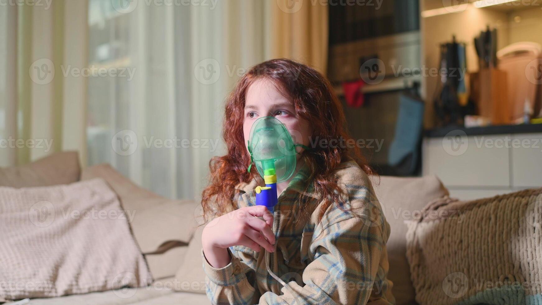 Sick girl making inhalation with nebulizer to reduce coughing, at home, child taking medication while breathing in through face mask. Bronchitis and asthma treatments for children photo