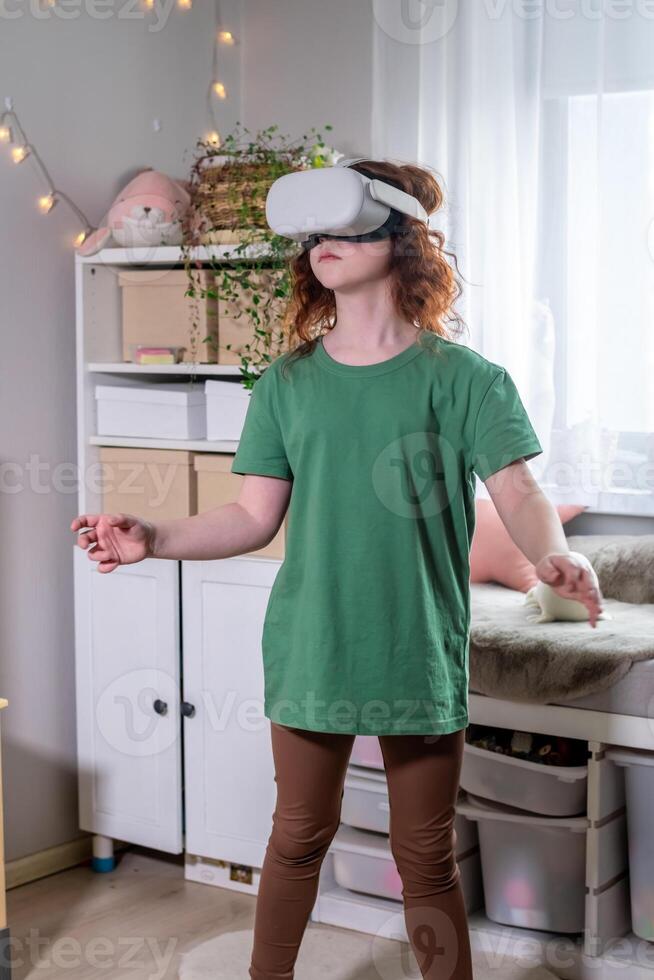 redhead teen girl at home in living room put on vr helmet to enjoy virtual reality online game cyber space world simulation. cute girl has fun using new electronic device for entertainment photo
