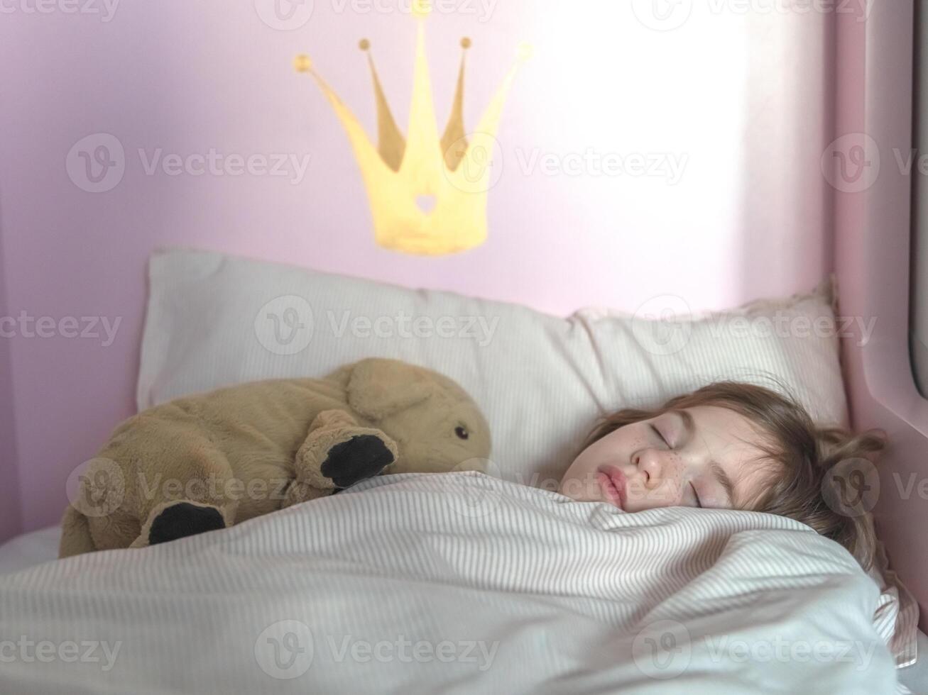 cute little girl sleeps in bed with plush toy photo