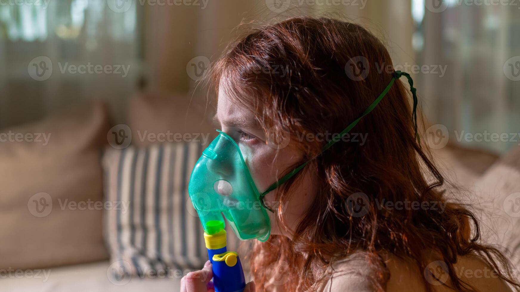Sick girl making inhalation with nebulizer to reduce coughing, at home, child taking medication while breathing in through face mask. Bronchitis and asthma treatments for children photo