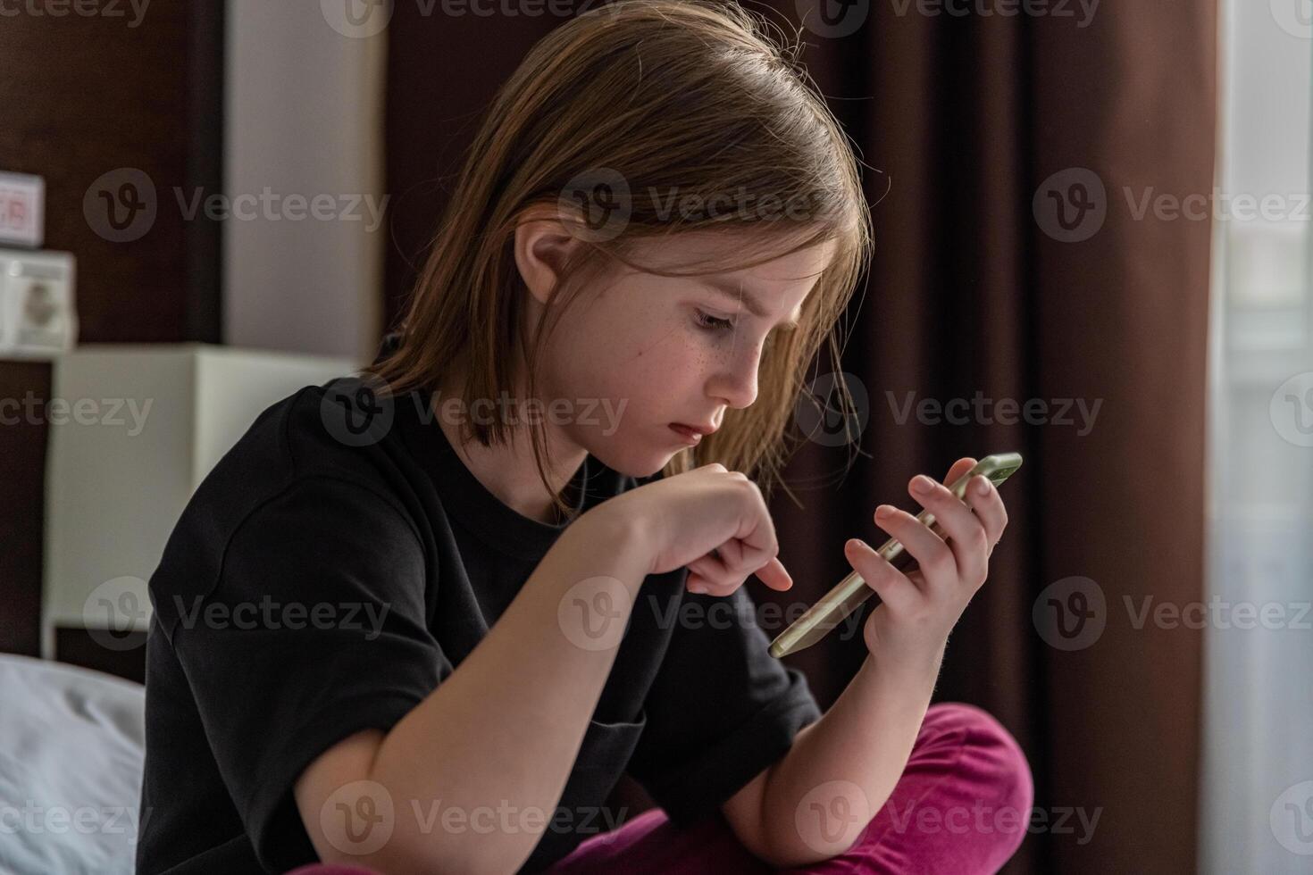 cute little girl on the bed with mobile phone photo