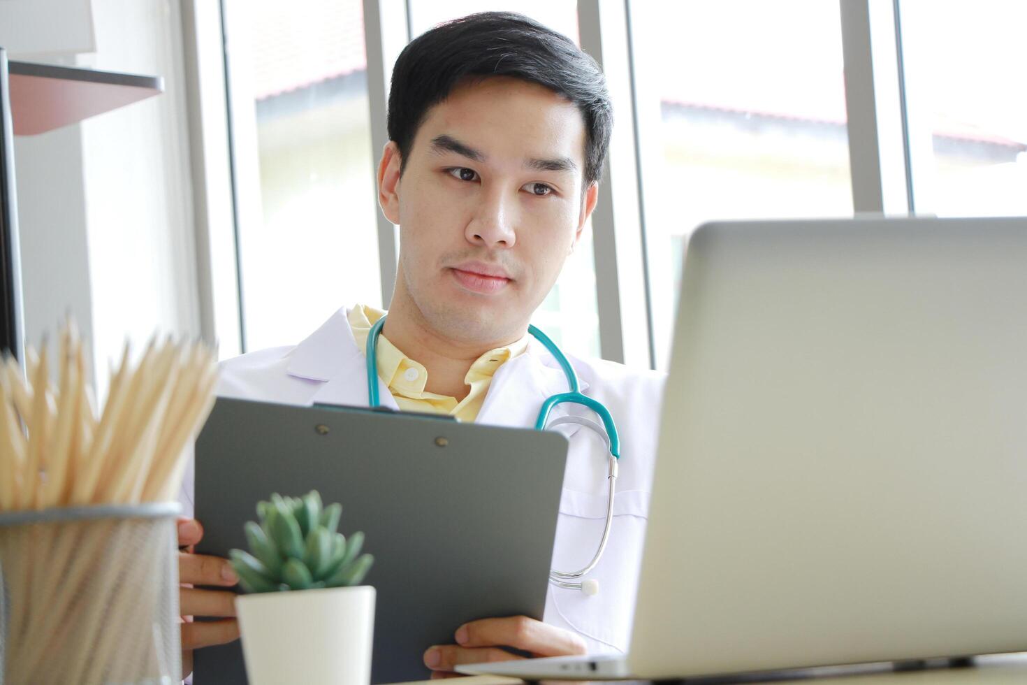 Smiling Professional Asian Psychiatrist man is studying and researching for treatment Mental health patients at Medical Research Library. Doctor clinic office concept. photo
