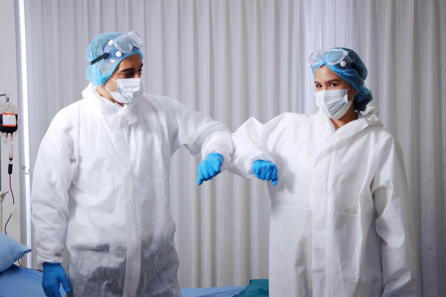 Caucasian and Asian Medical team in Personal Protective Equipment or PPE clothing and Healing for patient infected with the Covid-19 virus is Elbow and arms collide in hospital of Thailand photo