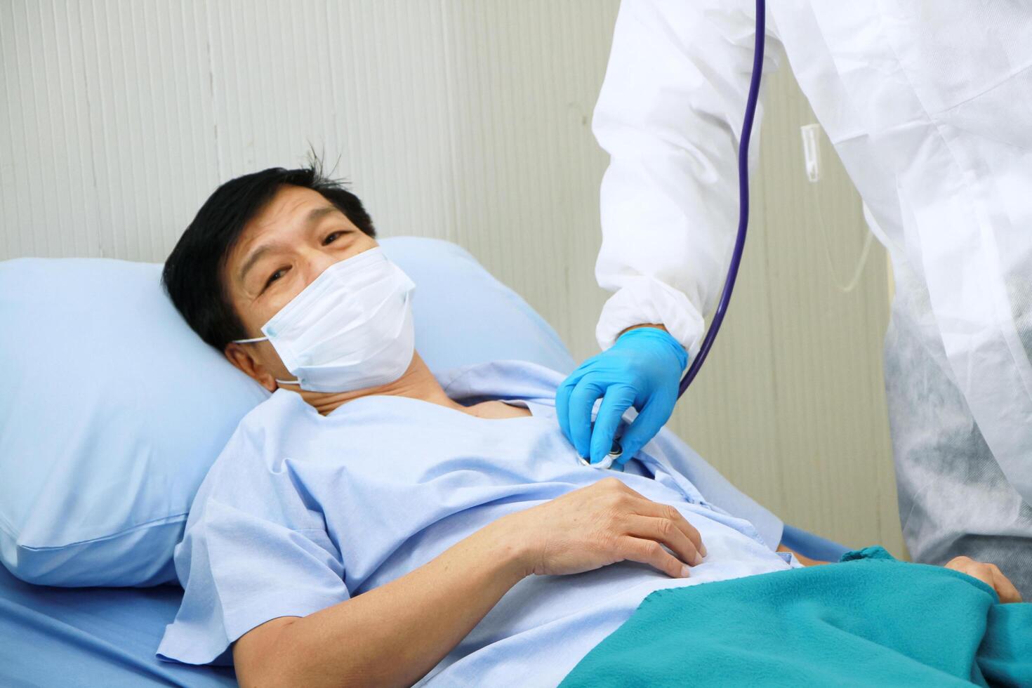 Medical team in Personal Protective Equipment or PPE clothing and use a respirator for asian old man patient is Respiratory system infected with Covid 19 virus and research with tablet for treatment. photo