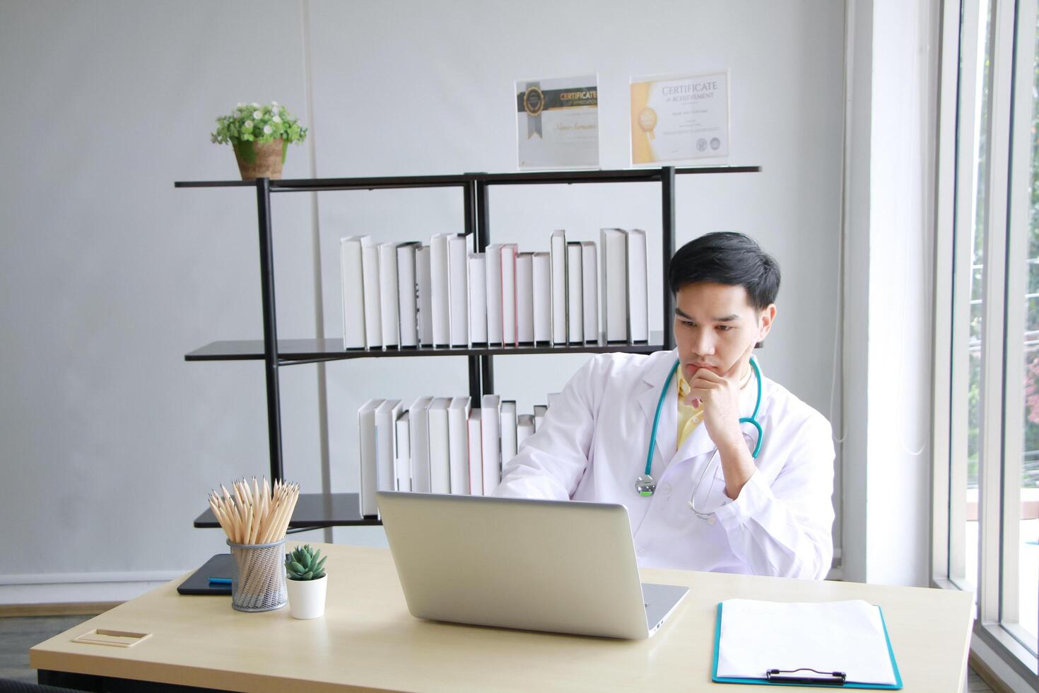 Serious Asian Psychiatrist man is researching with laptop for mental health problems in clinical. Major depressive disorder patients and healthcare Concept. photo