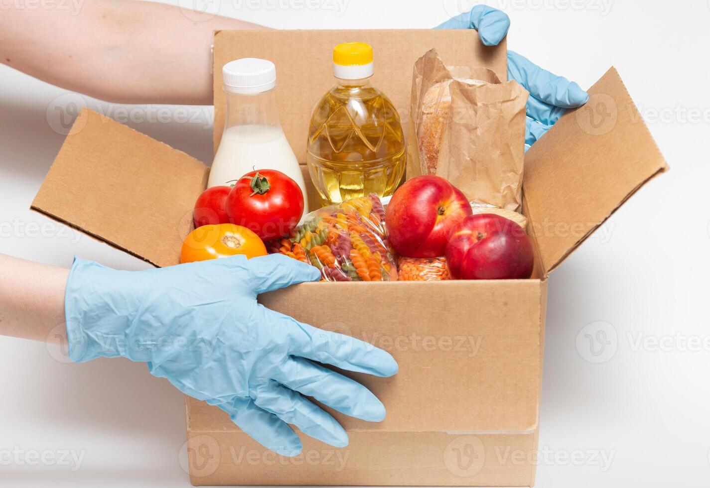 Person in latex gloves has holding a box with ordered goods. Safe food delivery service under quarantine. Online food shopping service or donation concept. White background.High quality close-up photo