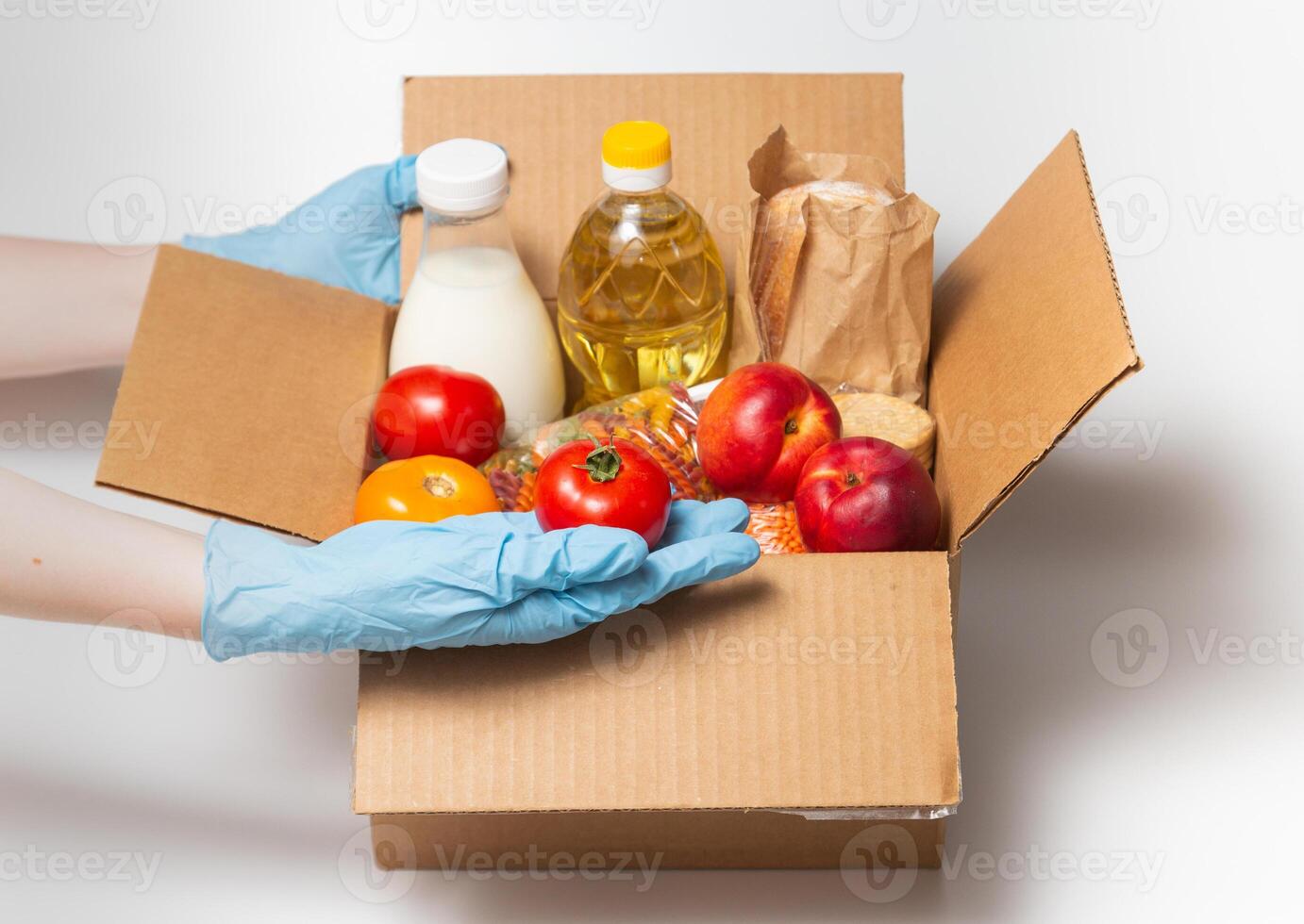 Person in latex gloves has holding a box with ordered goods.Safe food delivery service under quarantine. Online food shopping service or donation concept. White background.High quality close up photo