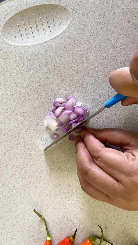 someone cutting onions with a knife on a cutting board with peppers photo