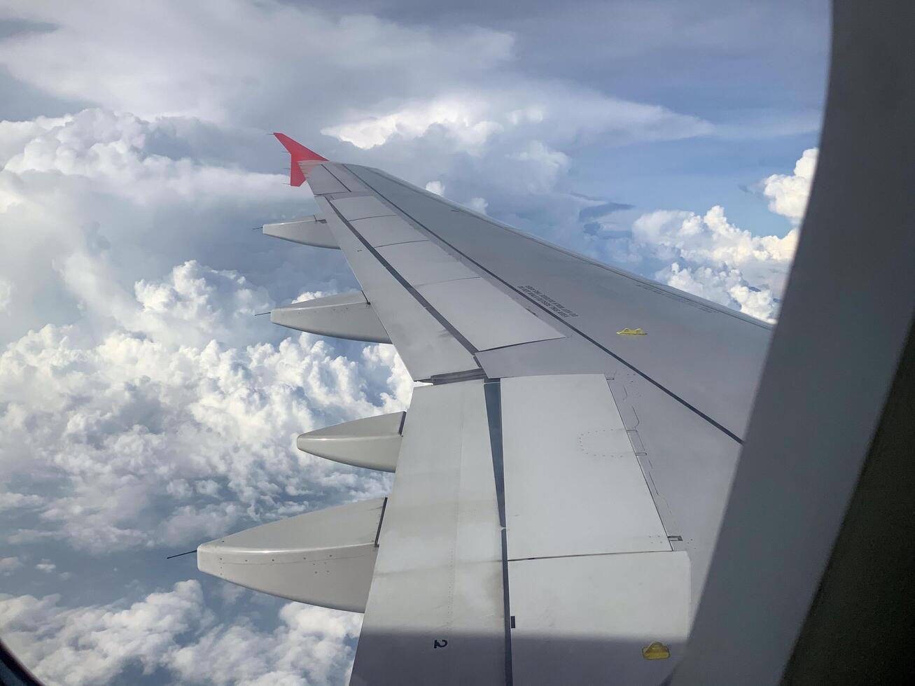 wing of an airplane flying in the sky with clouds photo