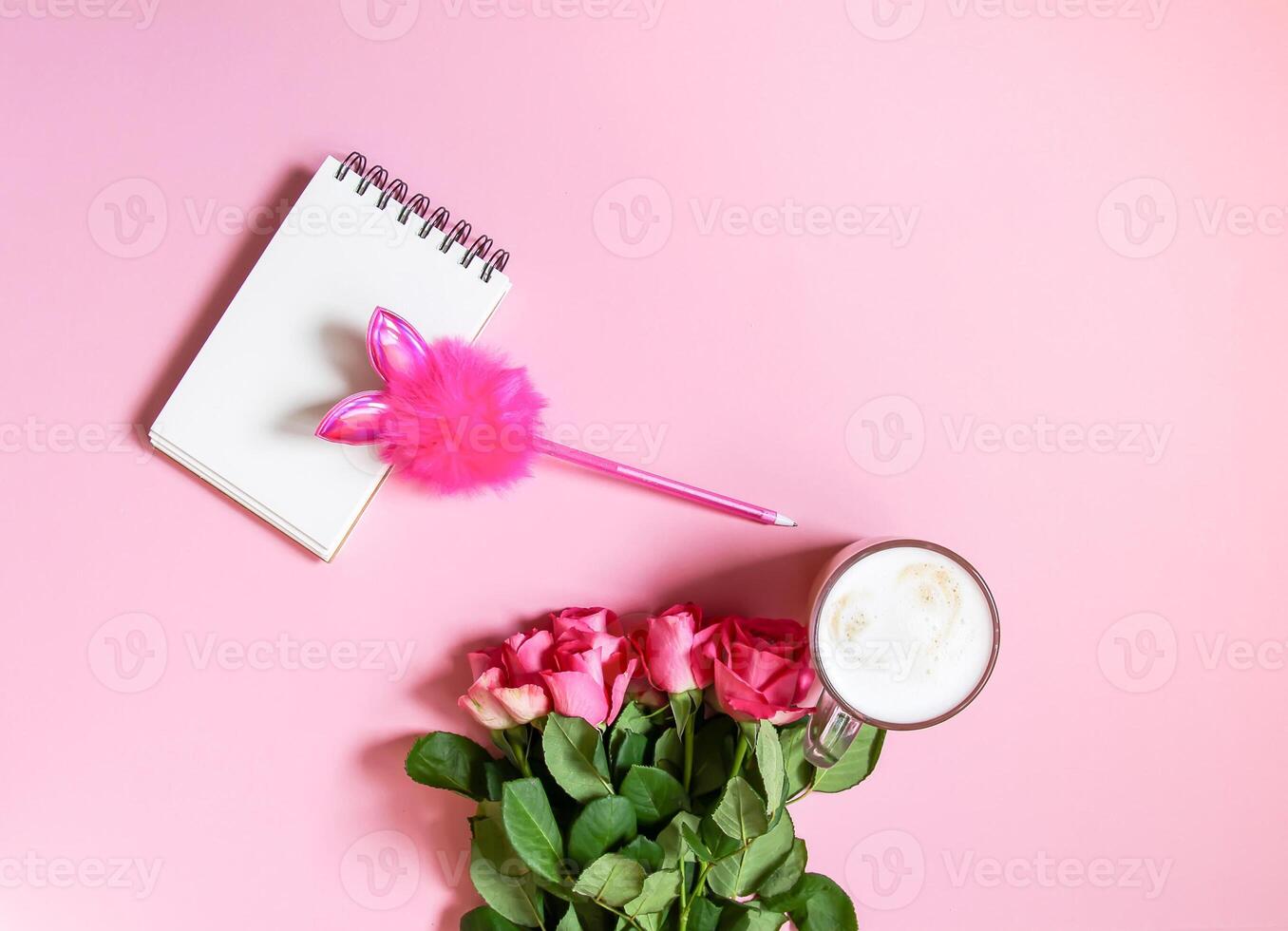 The cup of hot coffee, empty notepad with funny pen and bouquet of fresh roses on soft pink background. photo