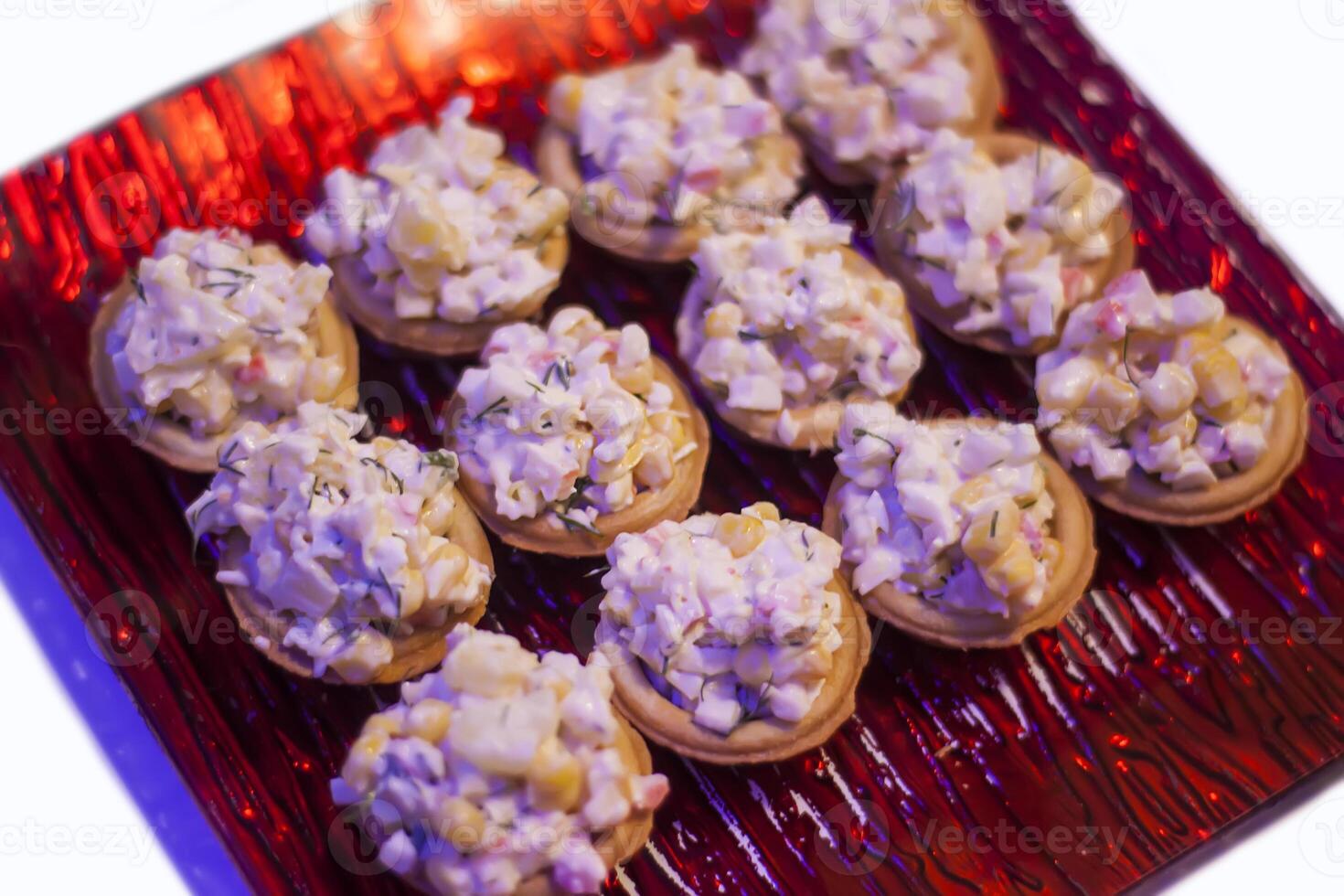 Tartlets or mini tarts with corn and crab salad on red plate photo