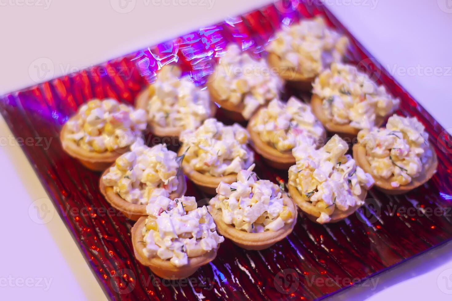 Tartlets or mini tarts with corn and crab salad on red plate photo