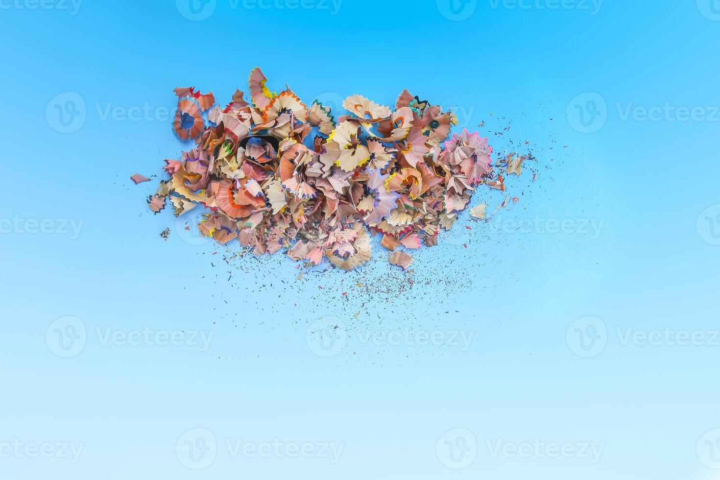Wooden pencil shavings and colorful crumbs of graphite from sharpener on soft pastel paper background. Top view. Design elements for poster, banner, cards photo