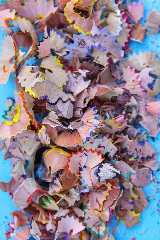Wooden pencil shavings and colorful crumbs of graphite from sharpener on soft pastel paper background. Top view. Design elements for poster, banner, cards photo