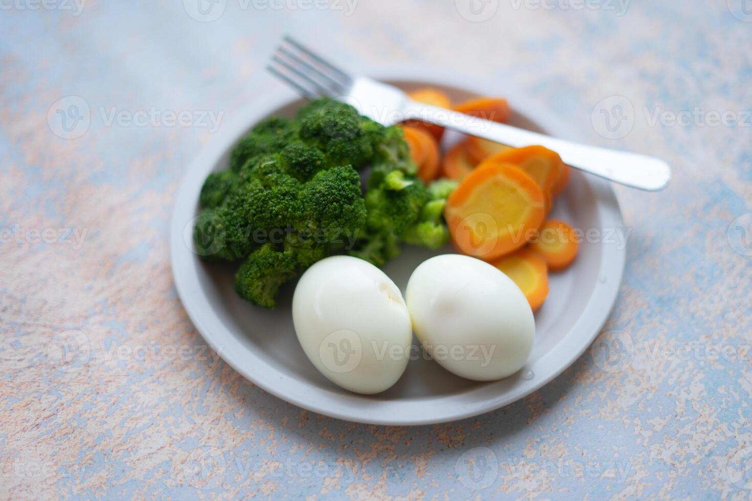 A breakfast diet plate without rice, featuring eggs, carrots, and broccoli, promoting a healthy and balanced meal photo
