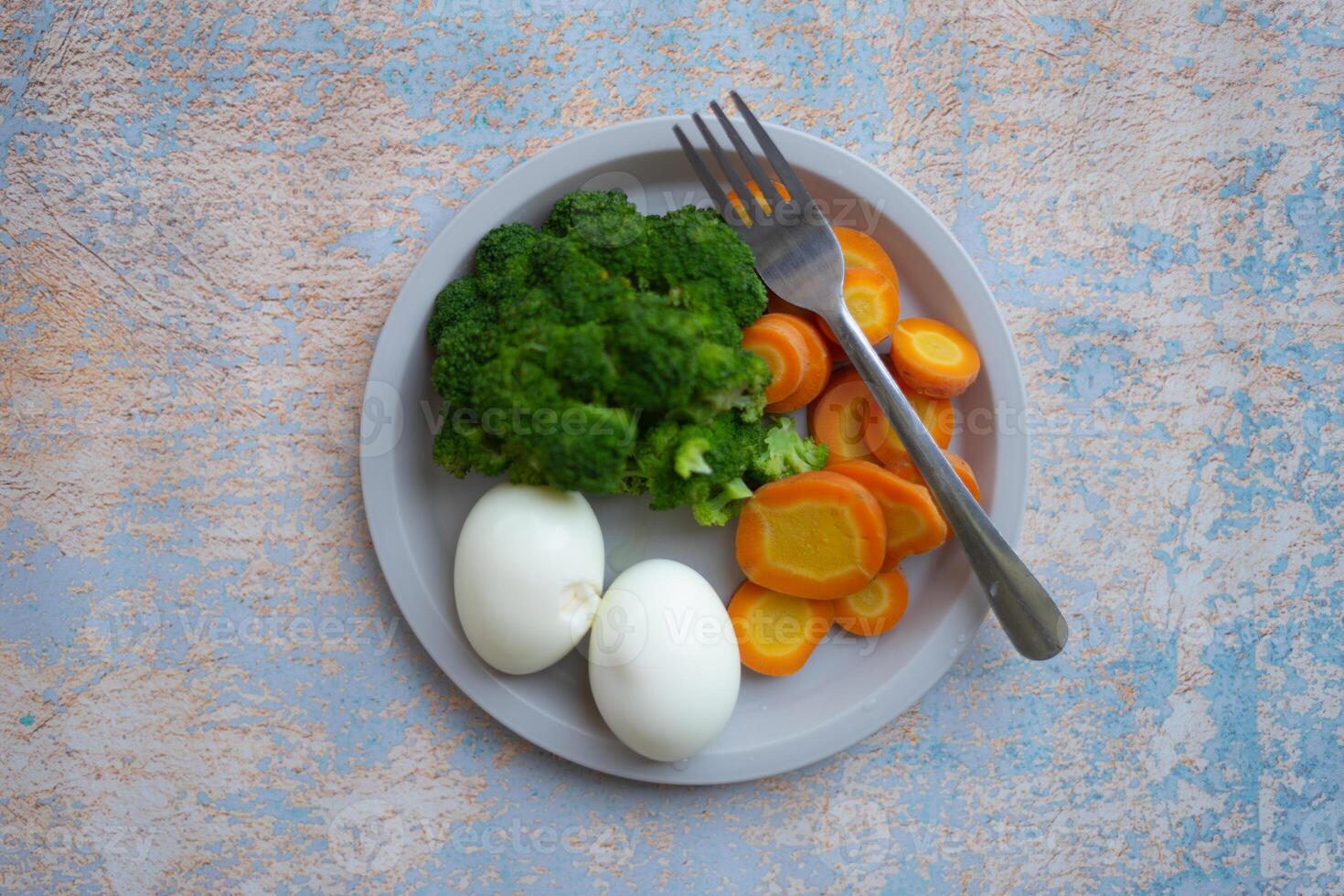 A breakfast diet plate without rice, featuring eggs, carrots, and broccoli, promoting a healthy and balanced meal photo