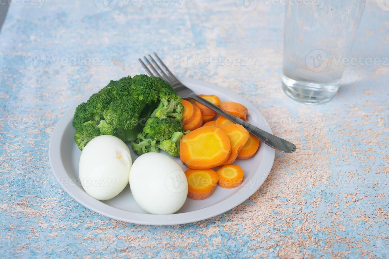 A breakfast diet plate without rice, featuring eggs, carrots, and broccoli, promoting a healthy and balanced meal photo