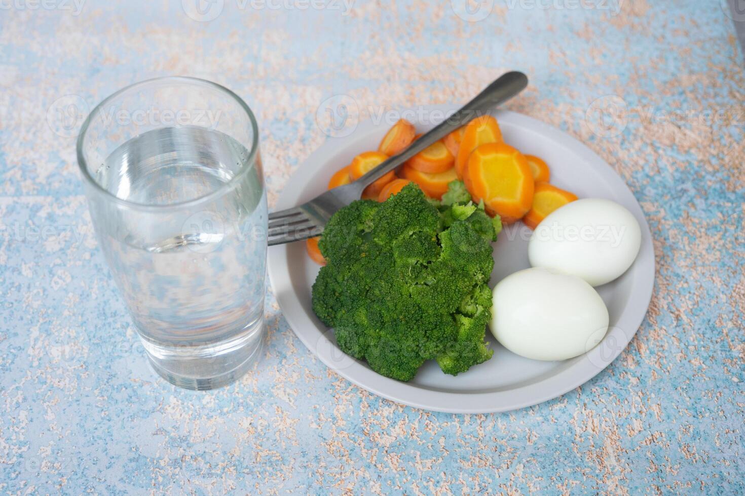 A breakfast diet plate without rice, featuring eggs, carrots, and broccoli, promoting a healthy and balanced meal photo