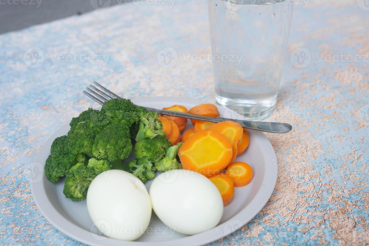 A breakfast diet plate without rice, featuring eggs, carrots, and broccoli, promoting a healthy and balanced meal photo