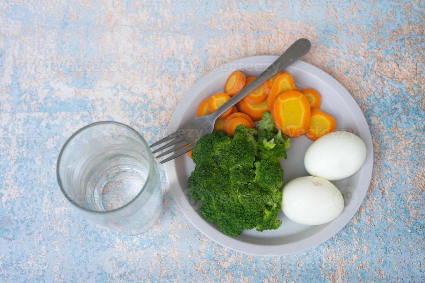 A breakfast diet plate without rice, featuring eggs, carrots, and broccoli, promoting a healthy and balanced meal photo