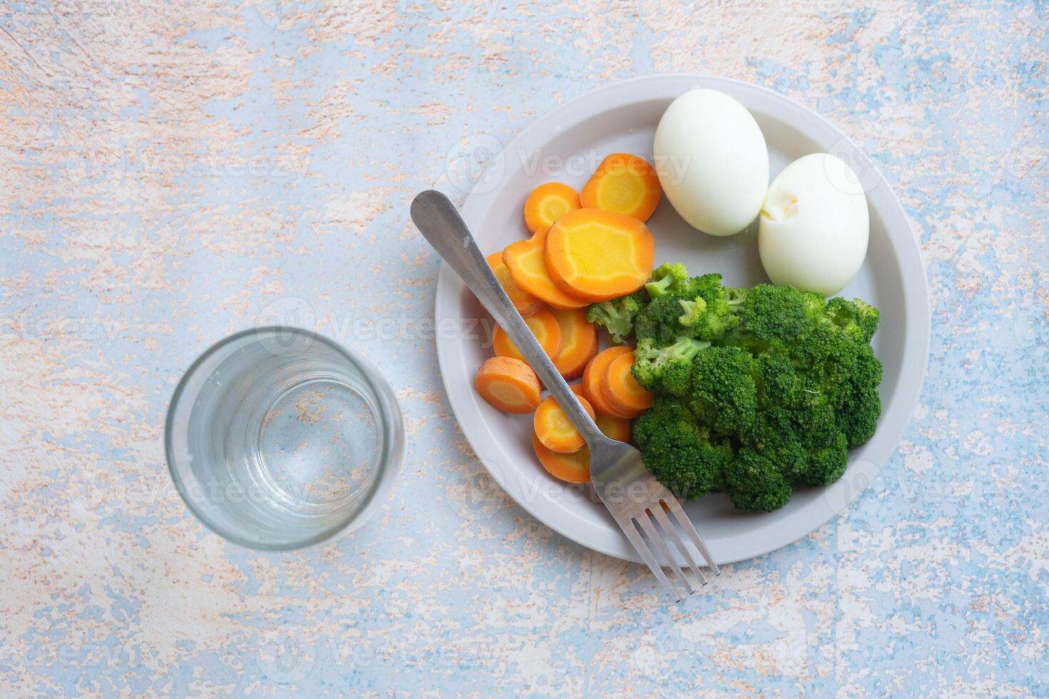 A breakfast diet plate without rice, featuring eggs, carrots, and broccoli, promoting a healthy and balanced meal photo