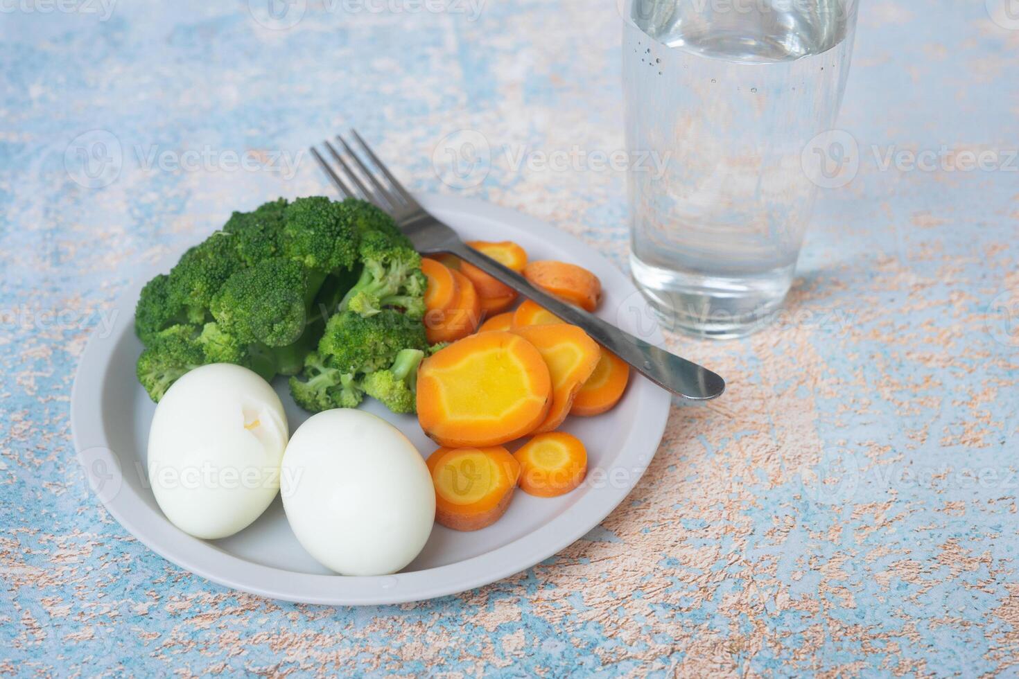 A breakfast diet plate without rice, featuring eggs, carrots, and broccoli, promoting a healthy and balanced meal photo