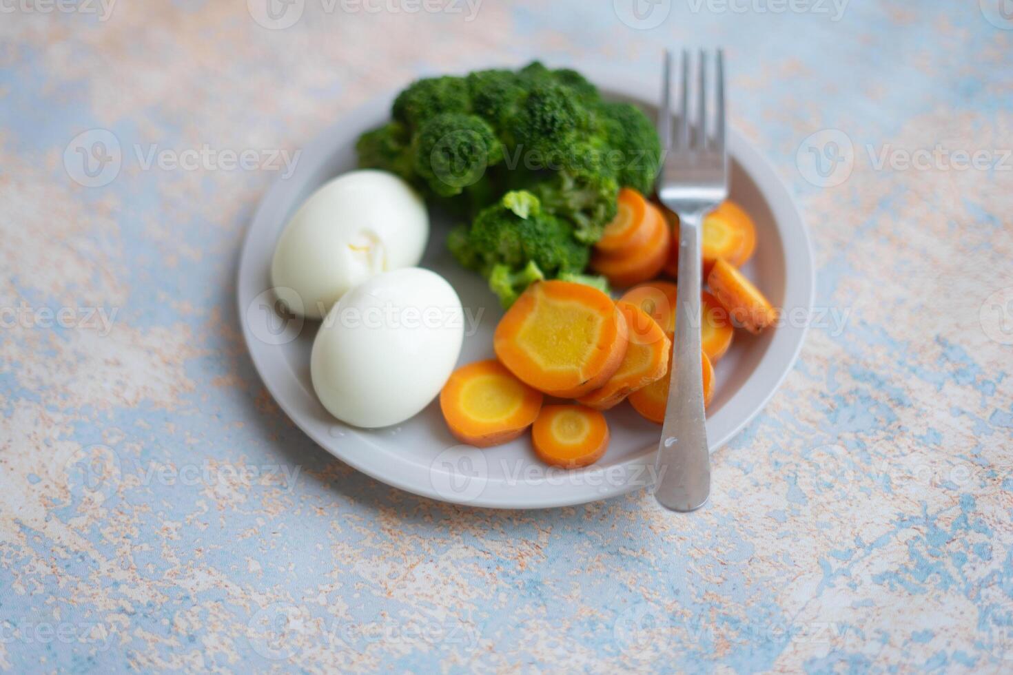 A breakfast diet plate without rice, featuring eggs, carrots, and broccoli, promoting a healthy and balanced meal photo