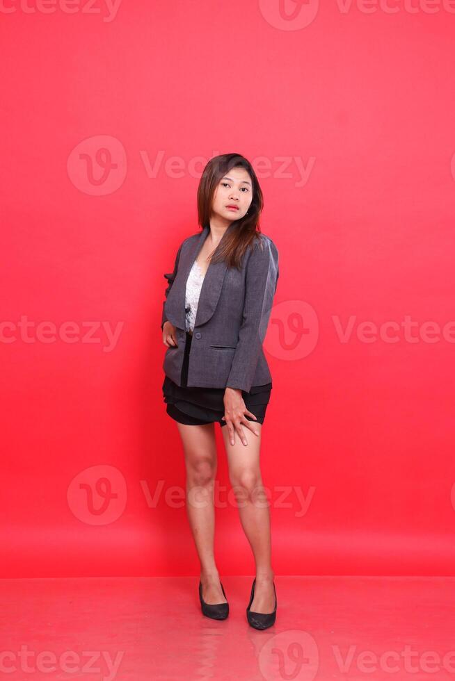 full body asian girl in elegant gray suit holding thigh long hair, white skin in studio on red background. for corporate concepts, fashion and advertising photo