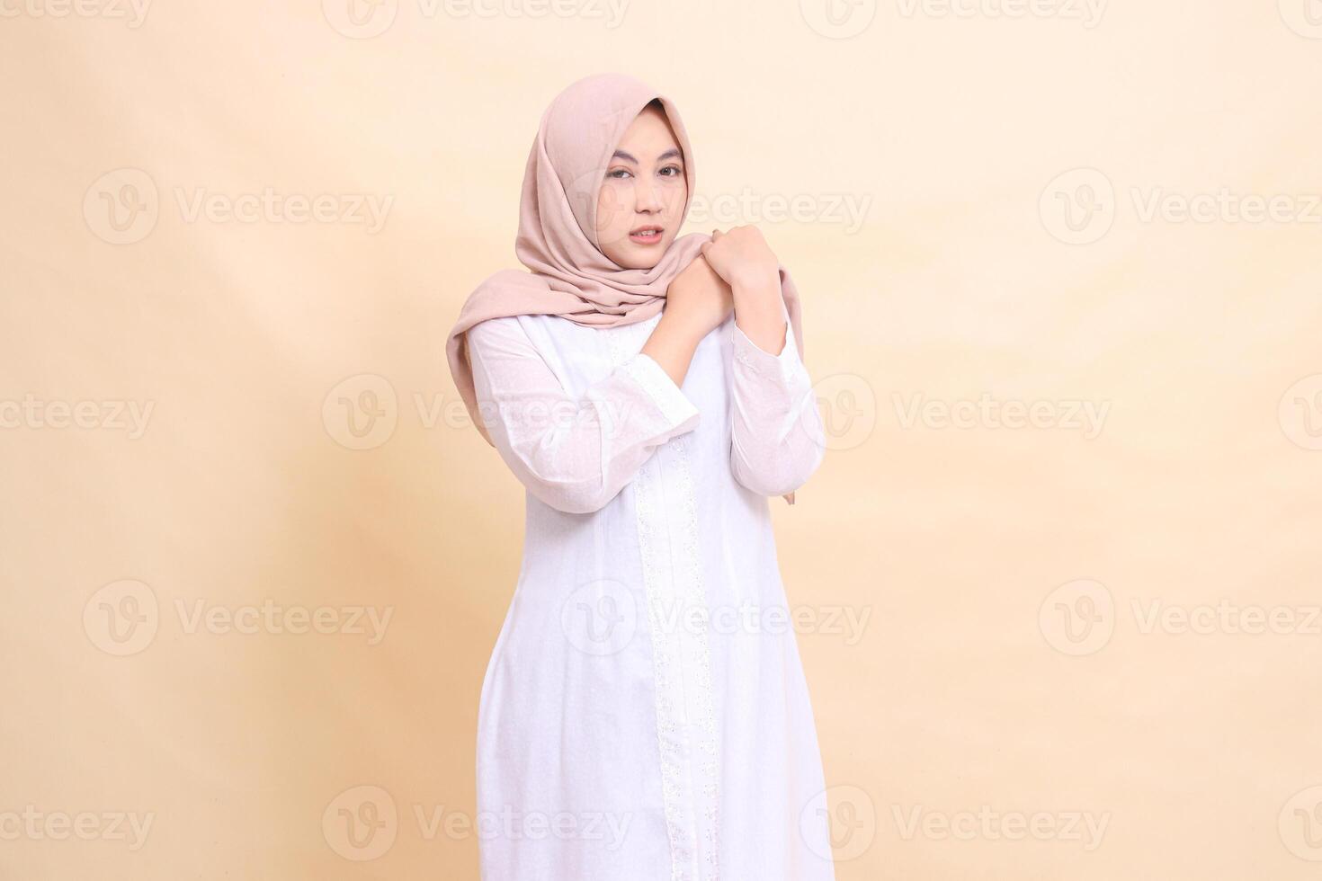 girl asian wearing a white hijab dress stands in pain with both hands holding her shoulders shoulder pain. for health, care, education and science concepts photo