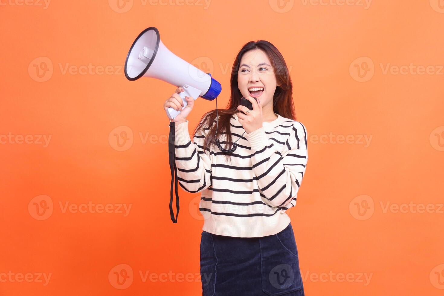 indonesia woman cheerful shouting expression using candid mic standing holding megaphone loudspeaker to make an announcement. for fashion, business and broadcast concepts photo