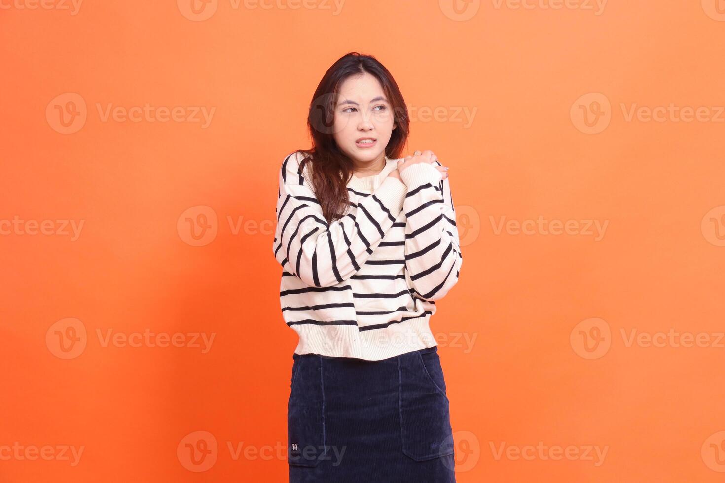 Beautiful candid Asian teenage woman isolated on orange background suffering from pain in shoulder after day's activities photo