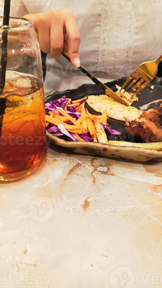 portrait of woman's hands enjoying dajaj mashwi, oven roasted chicken with tearing khubus pita bread with fork and knife on plate photo