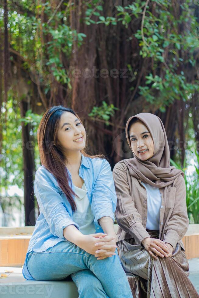 two happy Asian women friendship long time no see looking at the camera in the campus park. female students for education, promotion and lifestyle concepts photo