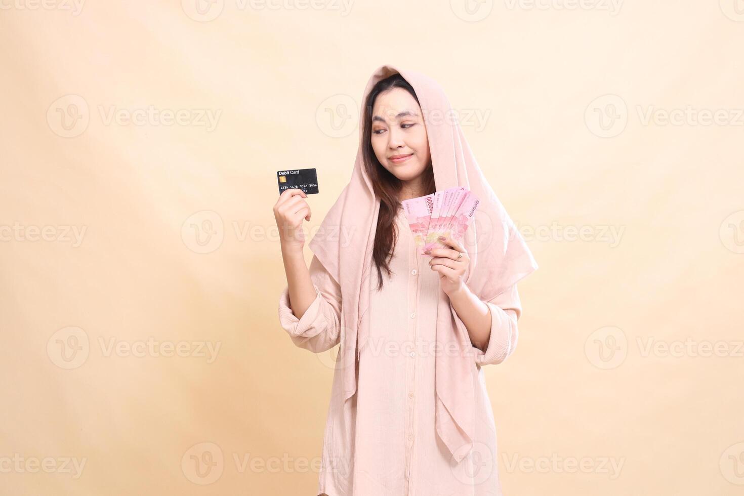 Asian woman candid smile expression hand holding debit card and carrying rupiah money. young beautiful for finance, advertising, fashion photo