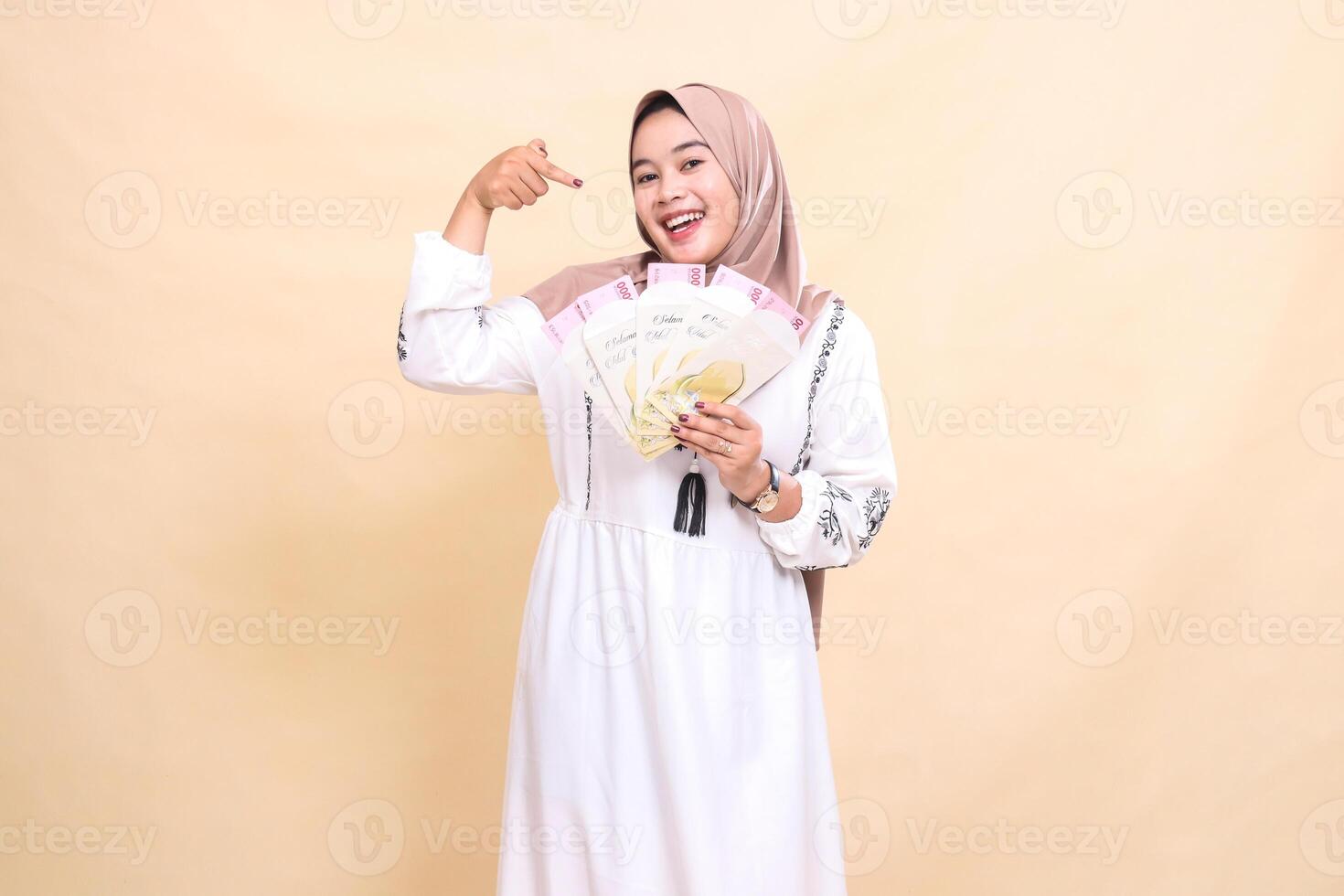 portrait of a beautiful Asian Muslim woman wearing a hijab, smiling cheerfully, receiving a gift or fitrah on Eid. used for advertising, giveaways, Eid and Ramadan photo