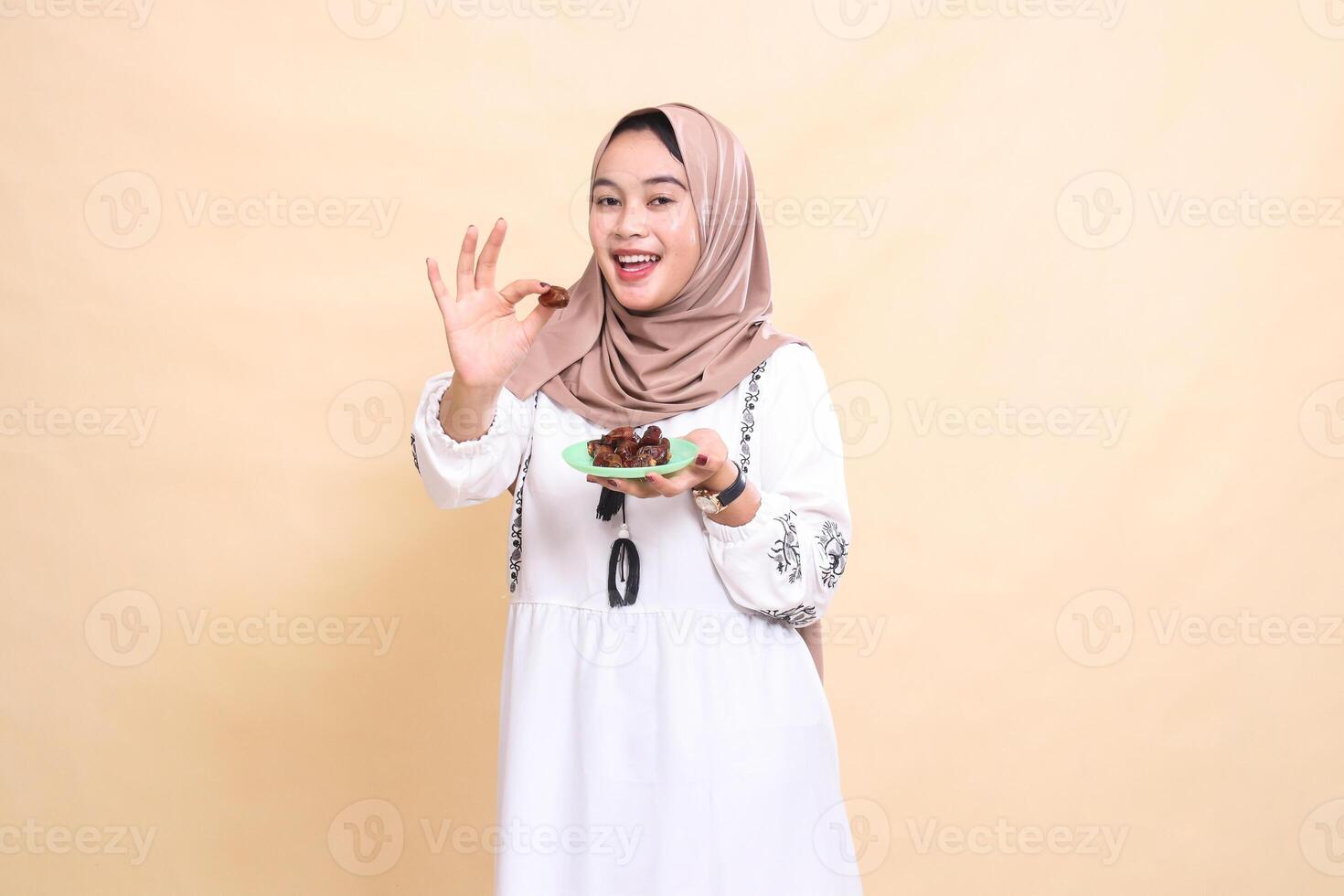 a beautiful indonesia Muslim woman wearing a hijab with a cheerful smile took a date forward and brought some dates for sahur and breaking the fast. used for advertising, health, Eid and Ramadan photo