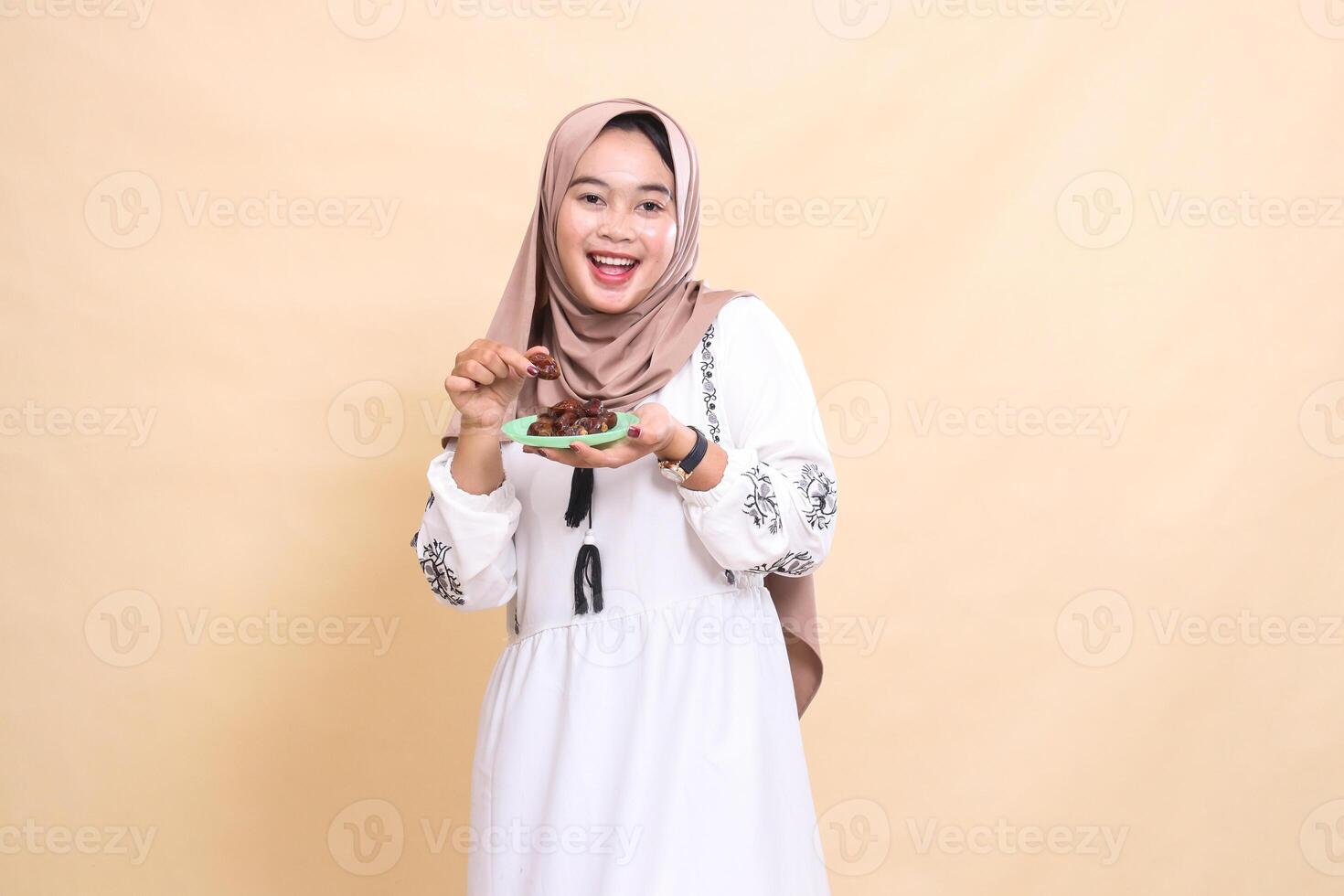 a beautiful indonesia Muslim girl wearing a happy hijab took a date and brought some dates for the sahur menu and breaking the fast. used for advertising, health, Eid and Ramadan photo