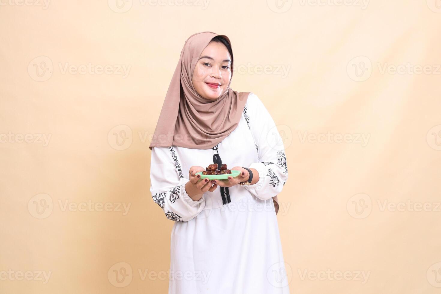 a beautiful Asian Muslim woman wearing a hijab with a cheerful smile brings dates for sahur and breaking the fast. used for advertising, health, Eid and Ramadan photo