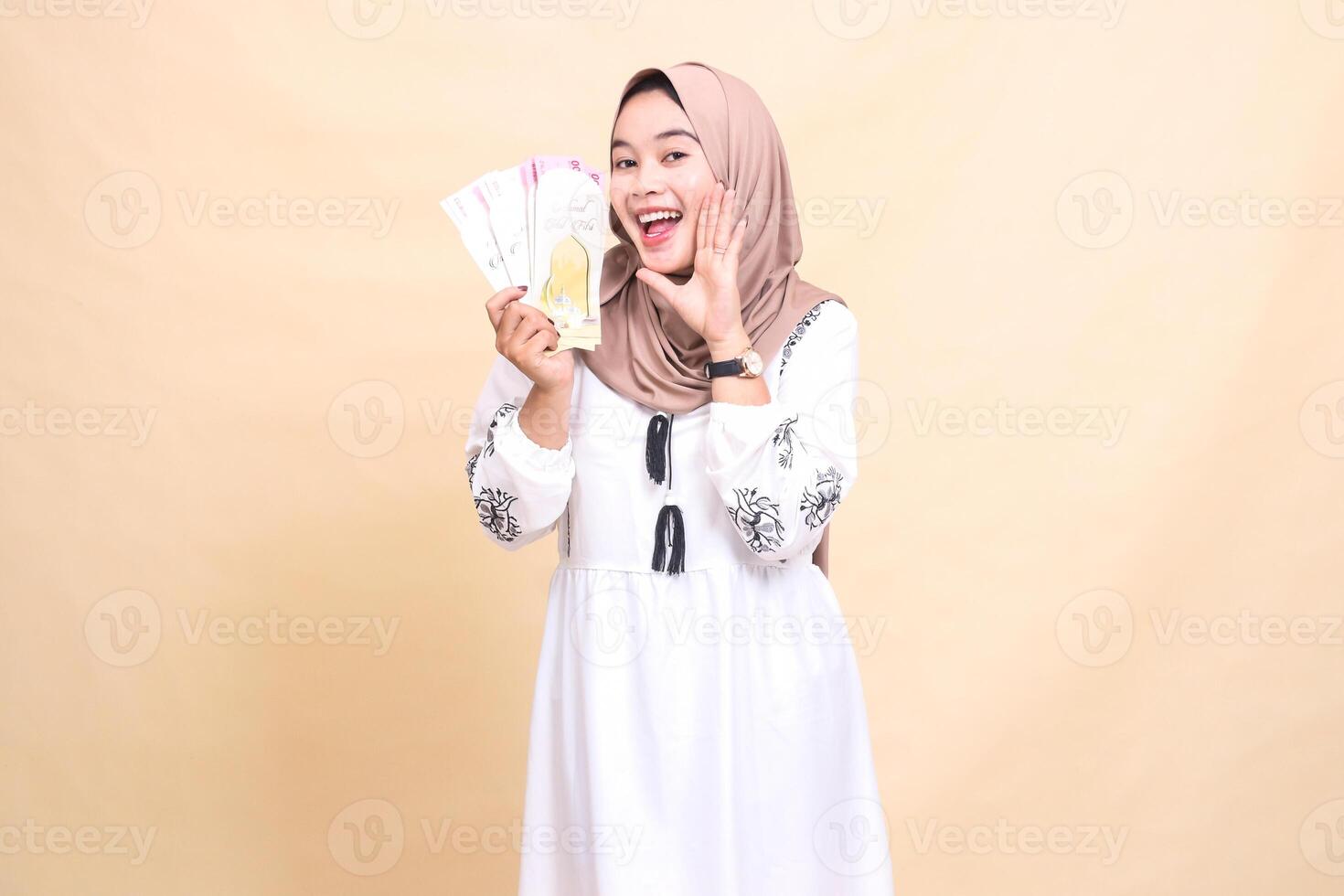 portrait of a beautiful Asian Muslim woman wearing a hijab, smiling cheerfully, showing off gifts and gifts while showing off gifts to the right on Eid. used for advertising, giveaways and Ramadan photo