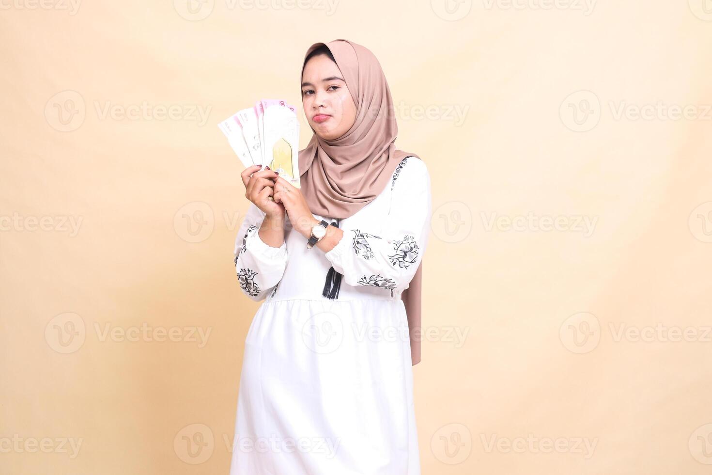 Portrait of a beautiful Asian Muslim woman wearing a hijab, sullenly holding and showing off gifts and gifts to the right on Eid day. used for advertising, giveaways, Eid and Ramadan photo