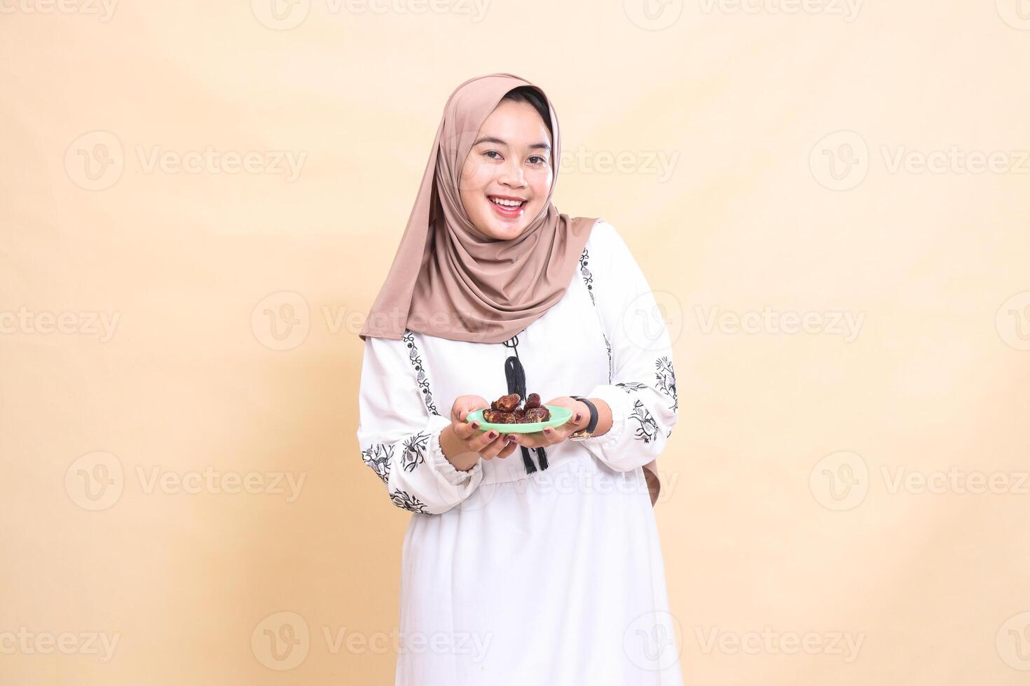 a beautiful Asian Muslim woman wearing a hijab with a cheerful smile brings dates for sahur and breaking the fast. used for advertising, health, Eid and Ramadan photo