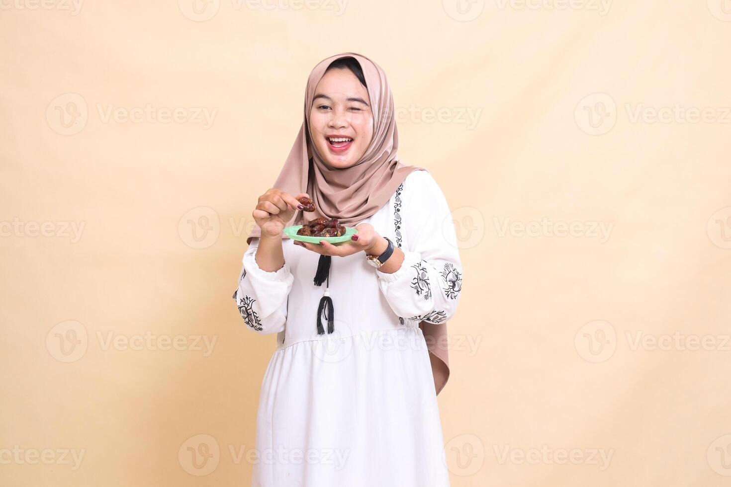 a beautiful Asian Muslim woman wearing a hijab happily winked, took a date and brought some dates for sahur and breaking the fast. used for advertising, health, Eid and Ramadan photo