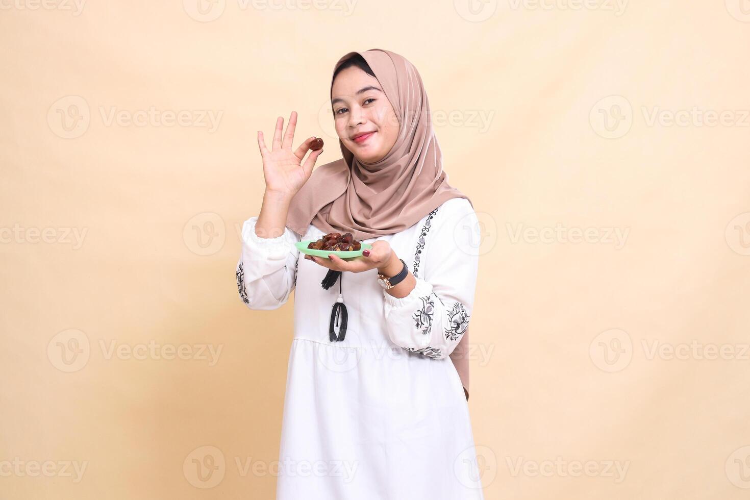 a beautiful Asian Muslim woman wearing a hijab smiled and took a date and brought some dates for the meal for sahur and breaking the fast. used for advertising, health, Eid and Ramadan photo