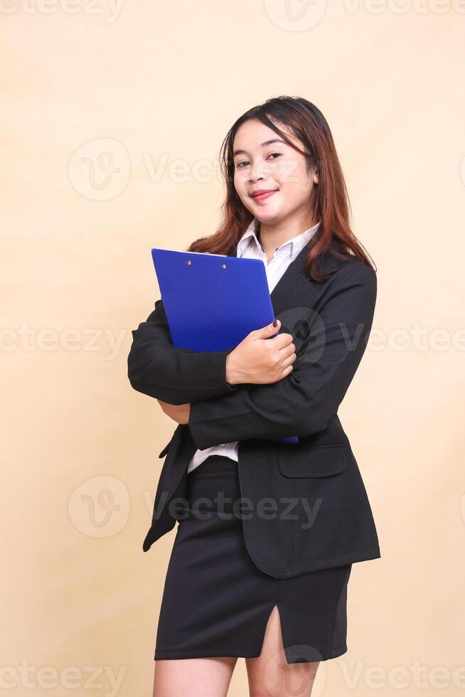 Beautiful formal Asian executive mature woman in suit smile standing and pose holding clipboard pen to camera, 3 by 4 body portrait on yellow background for commercial, vacancy and business photo