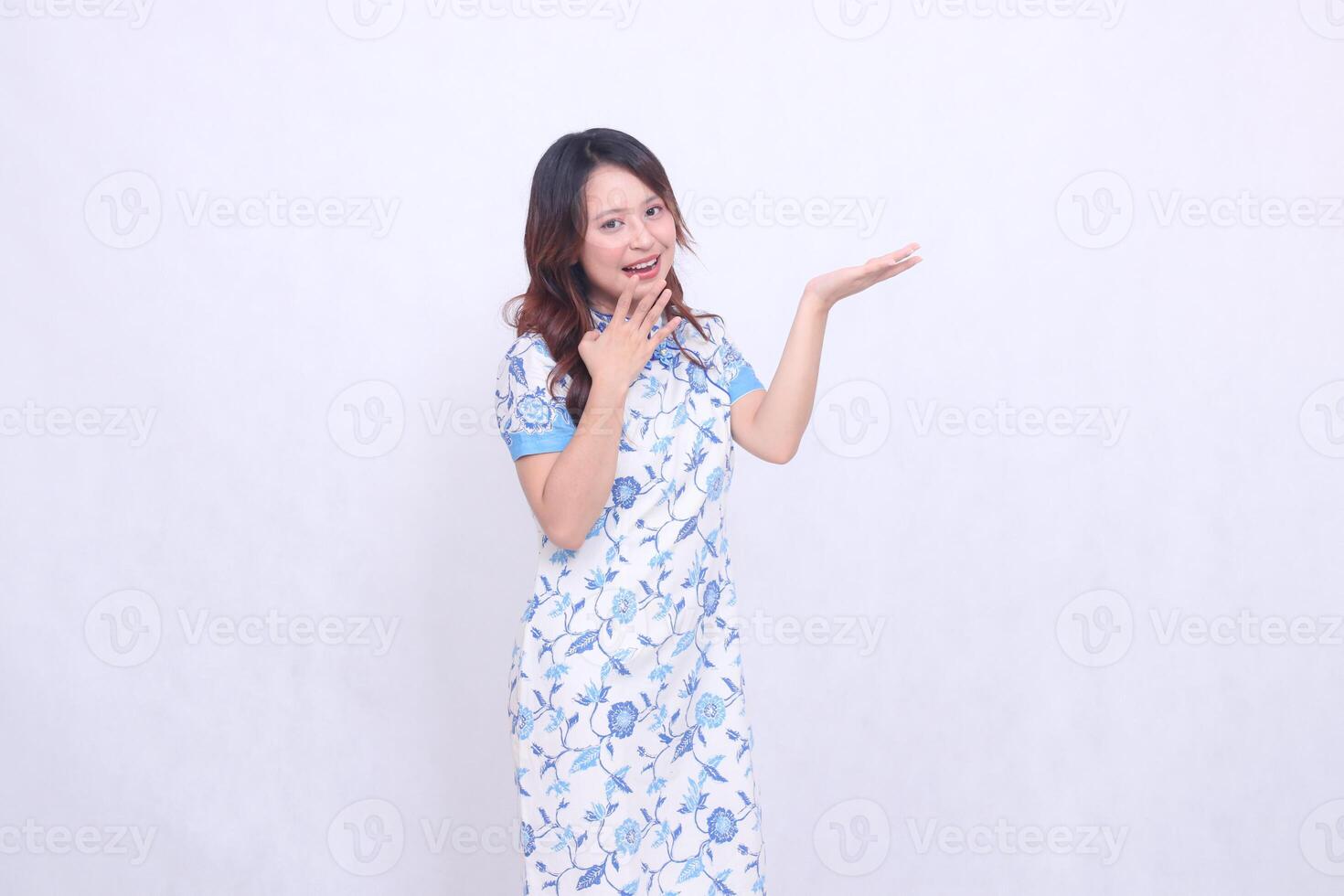 Beautiful cheerful Javanese Chinese woman wearing modern Chinese dress front view and hand presenting isolated white background. happy Chinese New Year photo