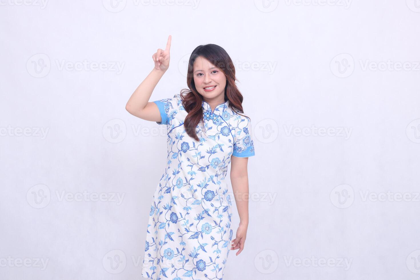 beautiful smiling chinese woman wearing modern chinese dress left hand pointing up on white background. happy Chinese New Year photo